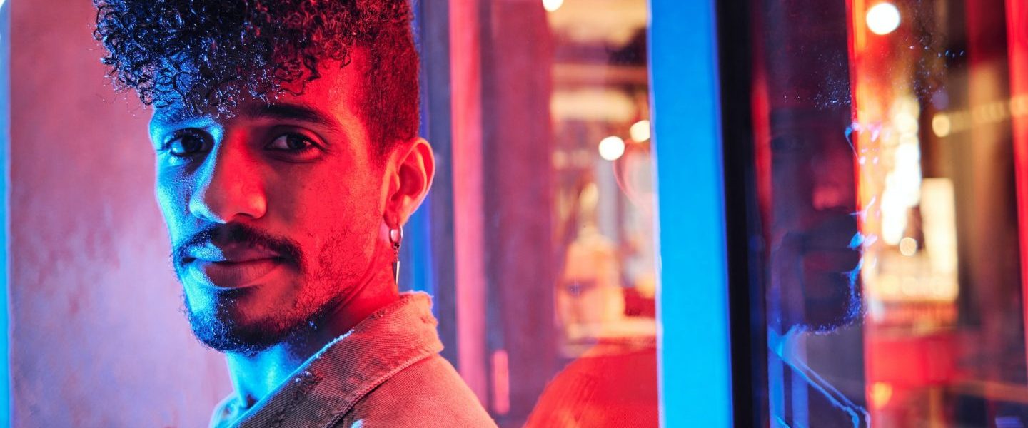 young-hispanic-man-close-to-a-neon-light-with-blue-and-red-lights-e1698314047406-1.jpg
