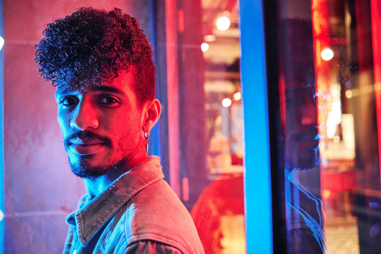 young-hispanic-man-close-to-a-neon-light-with-blue-and-red-lights-e1698314047406-1.jpg